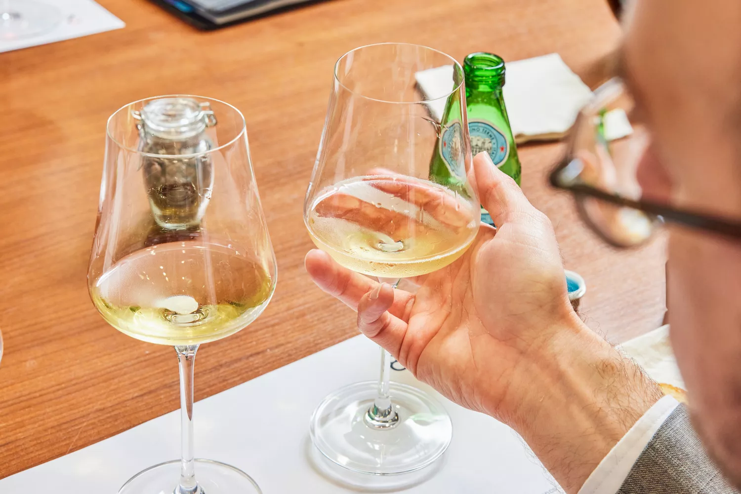 Person holding one of two Gabriel-Glas StandArt Crystal Wine Glasses Set glasses containing white wine in front of them