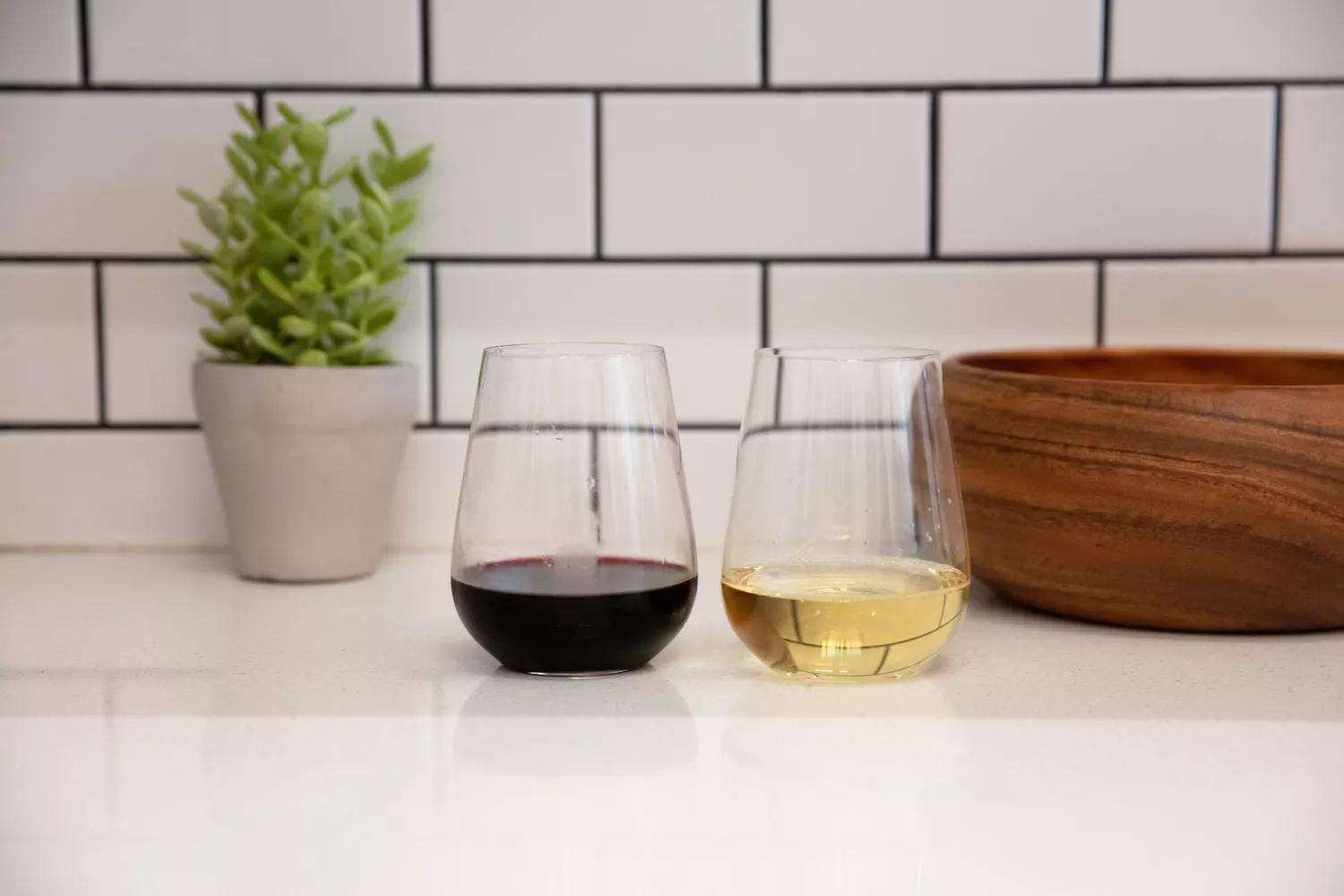 Two Glasvin The Stemless wine glasses on a white kitchen counter