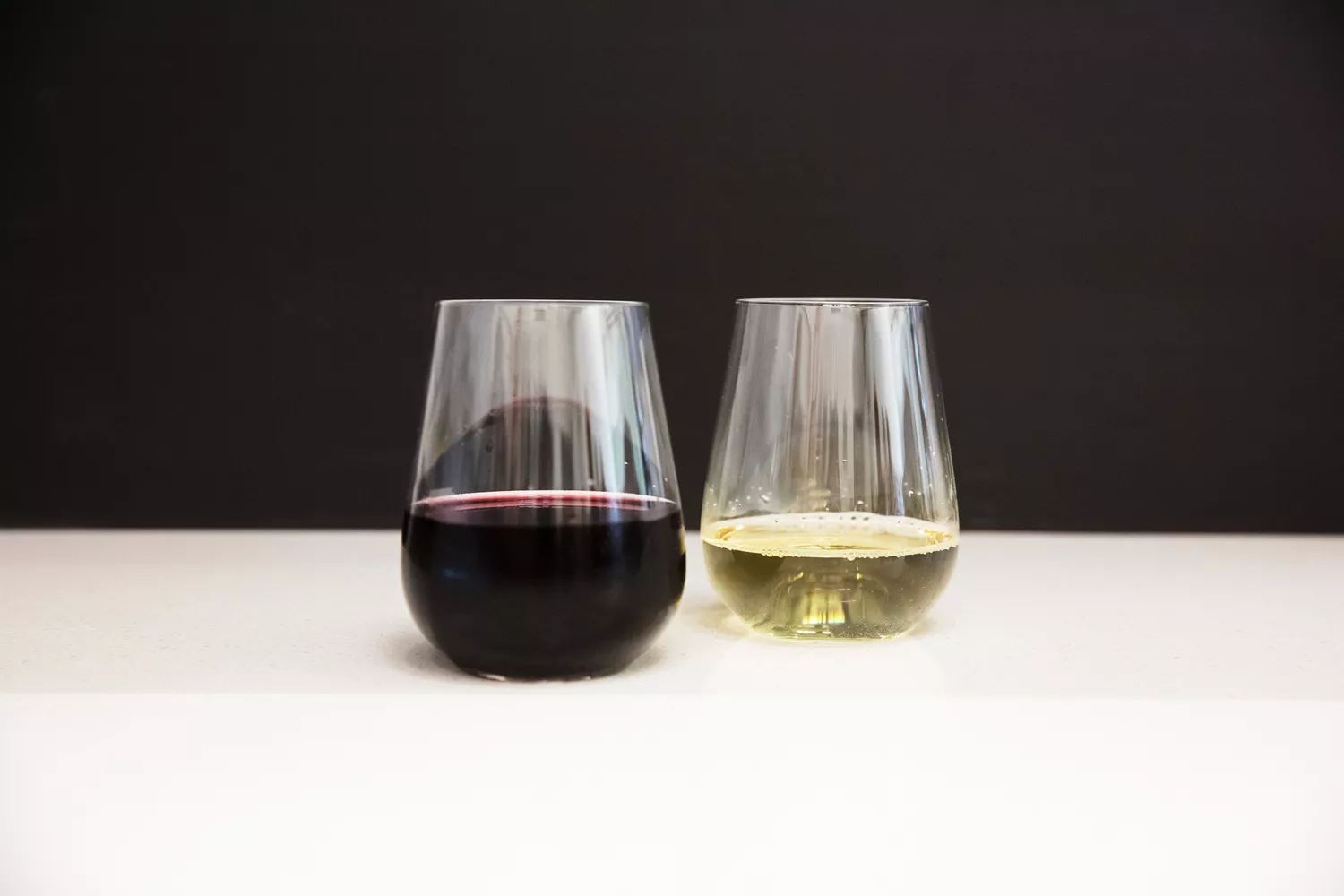 Two Glasvin The Stemless wine glasses on a white kitchen counter and a black background