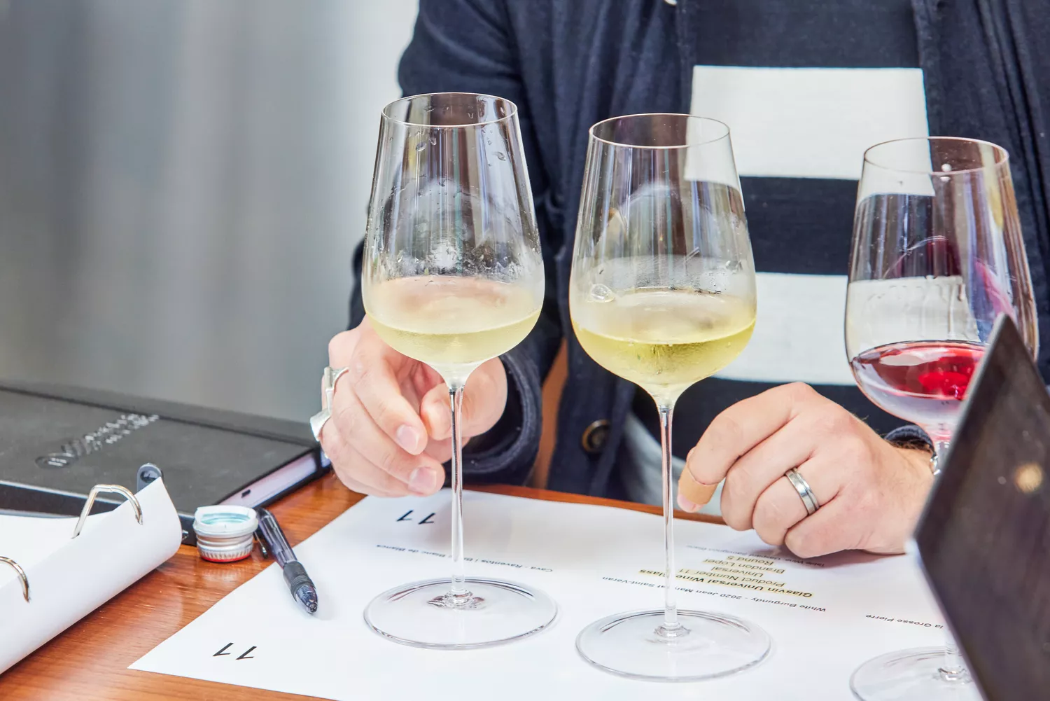Glasvin Universal Wine Glasses, Set of 2, containing white wine set on a sheet of paper in front of person