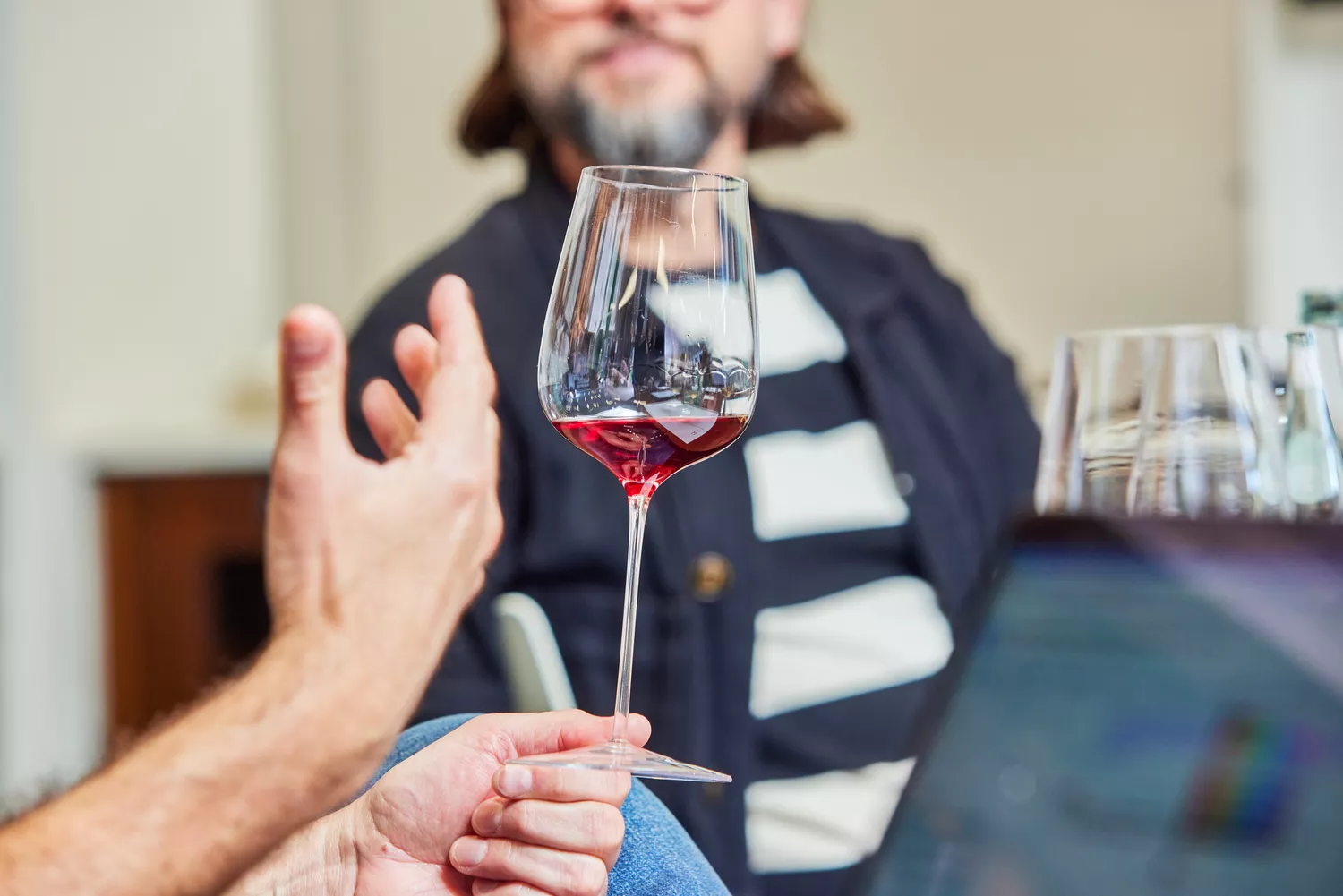 Hand holding Glasvin Universal Wine Glass containing red wine by the foot
